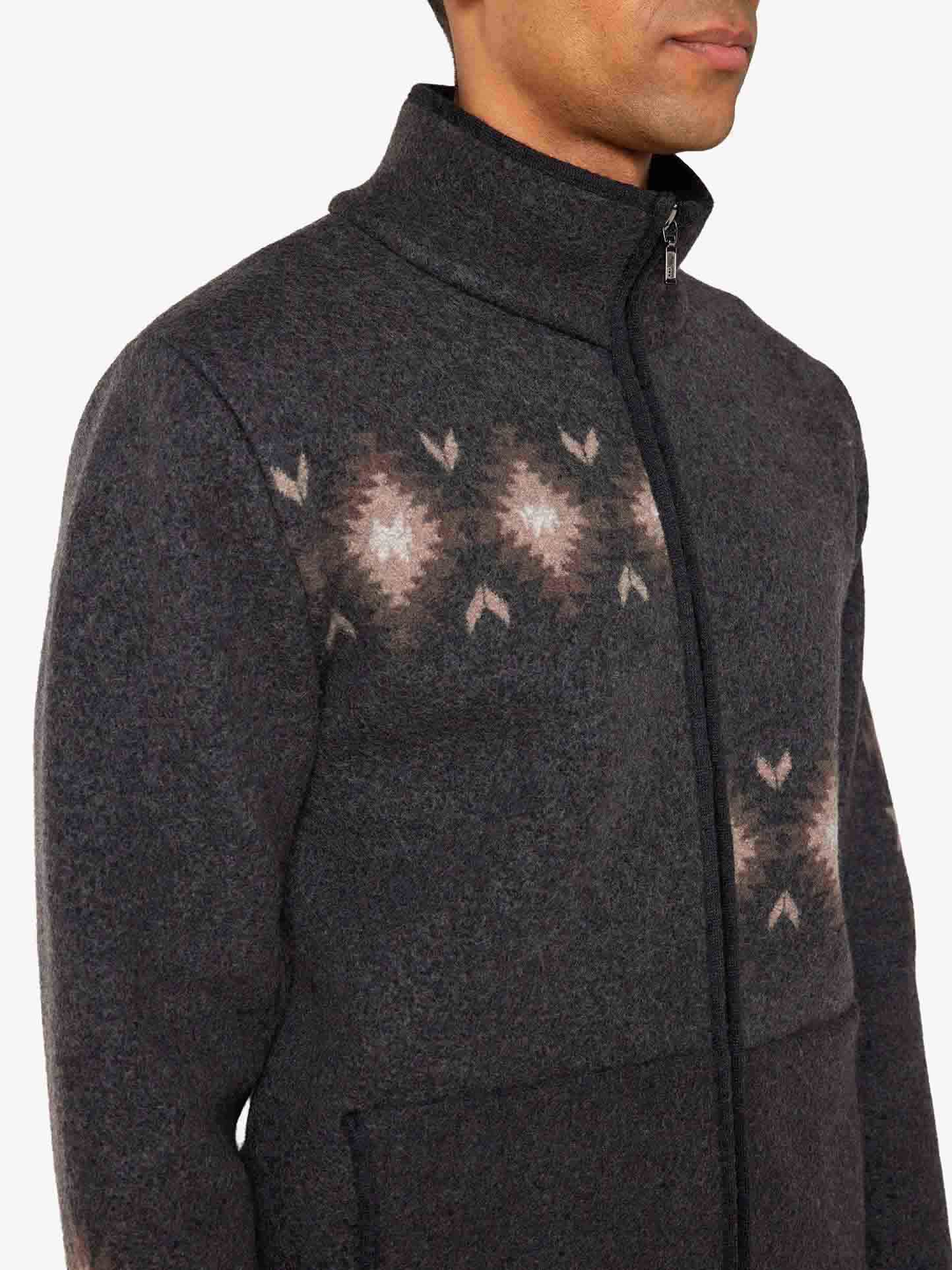 We Norwegians_FW25_Mens | Model is wearing the Hovden jacket | Color: Black | The jacket has a two-way zipper with a striking jacquard pattern inspired the Norwegian Sámi culture | Photograph focusses on neck and pattern details against a white background