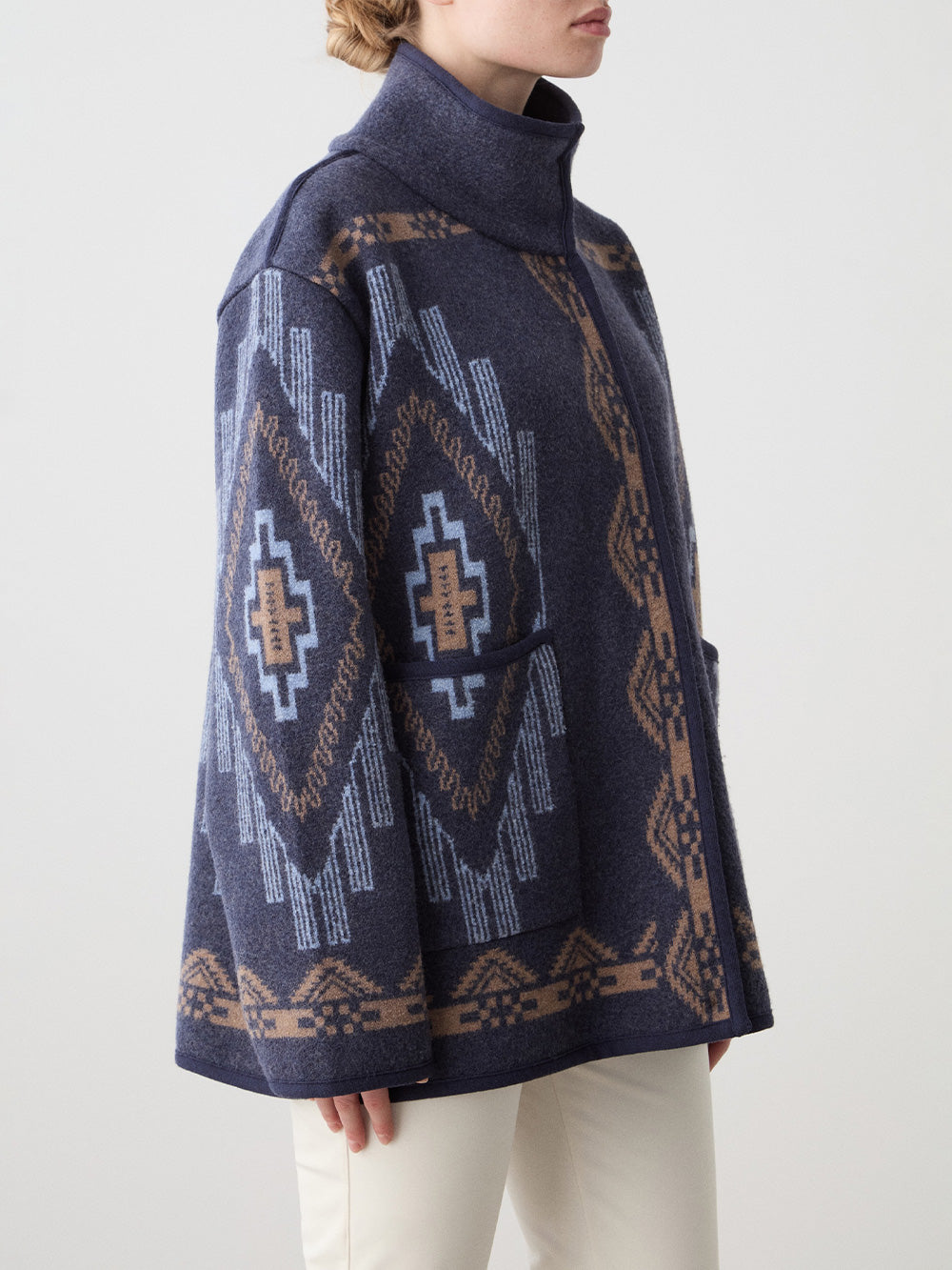 We Norwegians_FW25_Womens | Model is wearing the Kautokeino jacket in navy blue with off white Tyin bootleg ski pants | The jacket has a bold jacquard pattern inspired by Native and Indigenous American art | Photograph focussing on the pattern details against a white background