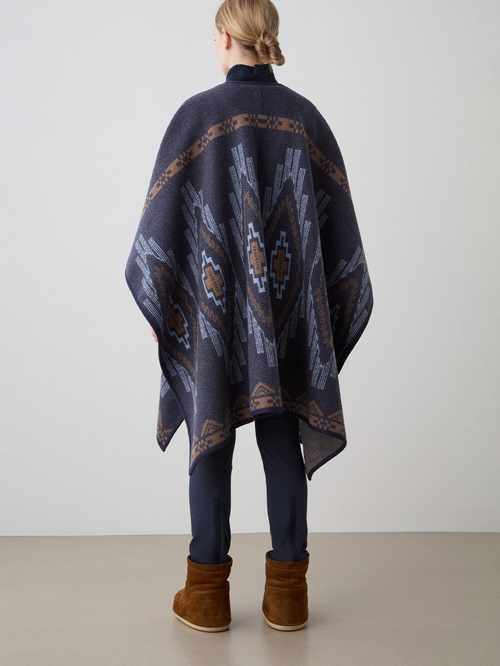 We Norwegians_FW25_Womens | Model is wearing the Kautokeino poncho | Navy Blue in color with a jacquard pattern inspired by Native and Indigenous American art | Made with boiled merino wool | Back view