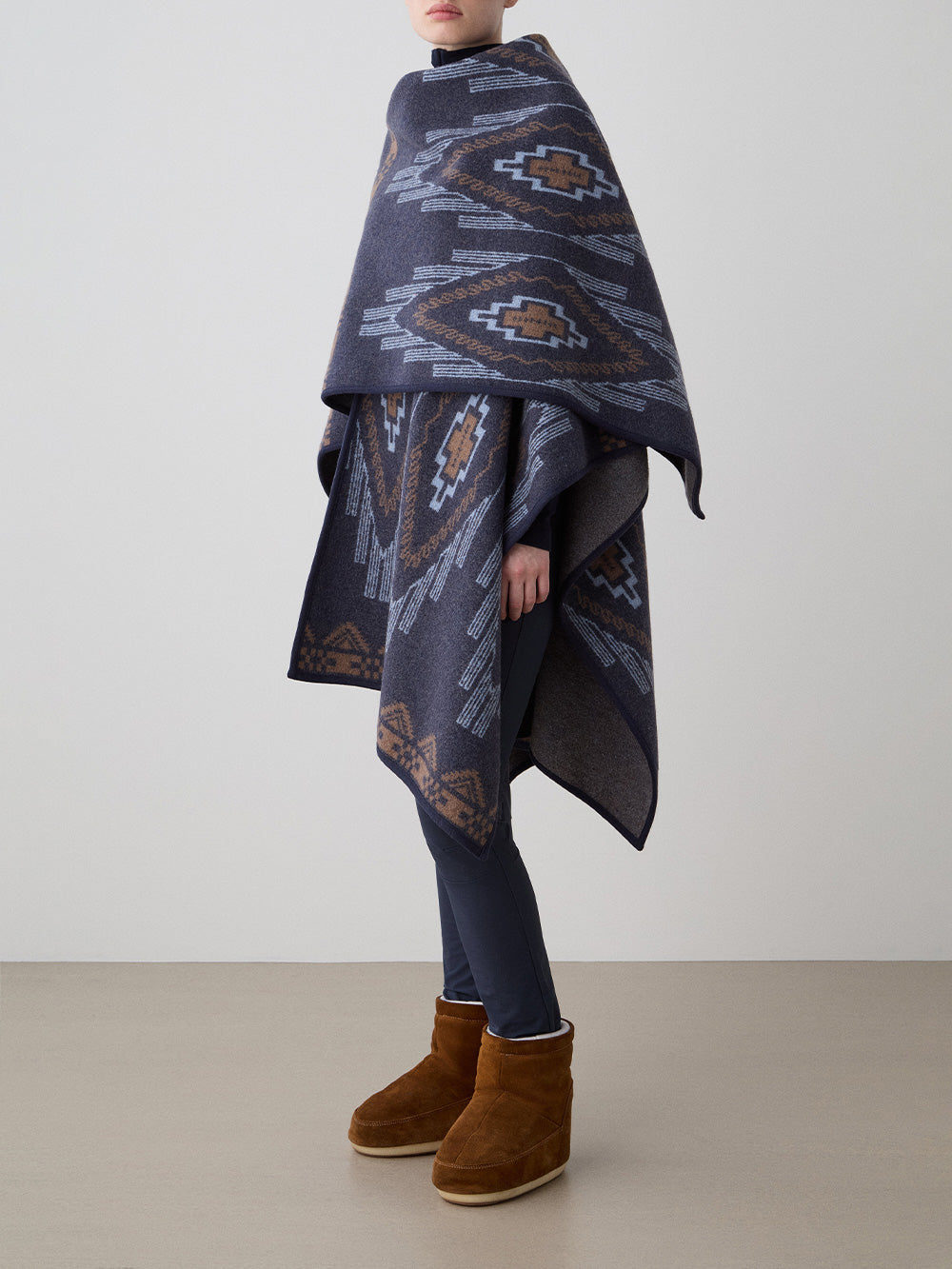 We Norwegians_FW25_Womens | Model is wearing the Kautokeino poncho | Navy Blue in color with a jacquard pattern inspired by Native and Indigenous American art | Made with boiled merino wool | Photograph is showing the fall and drape features of the garment