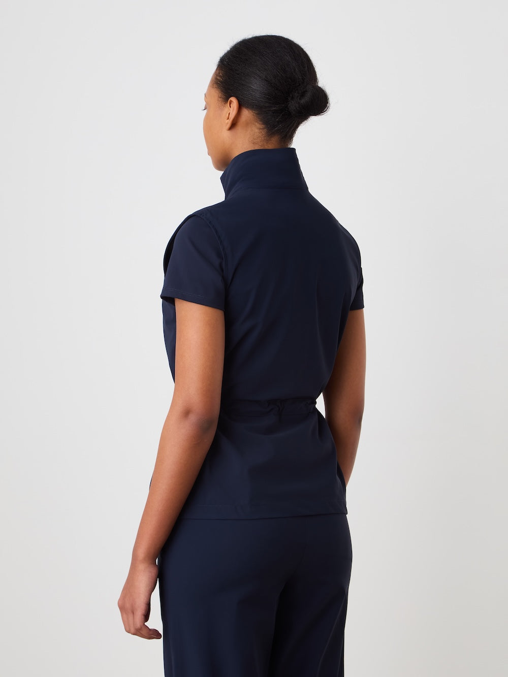 Person wearing a navy blue vest on a light background