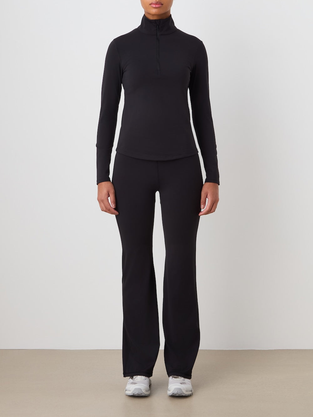 Person wearing a black turtleneck and pants set on a plain background