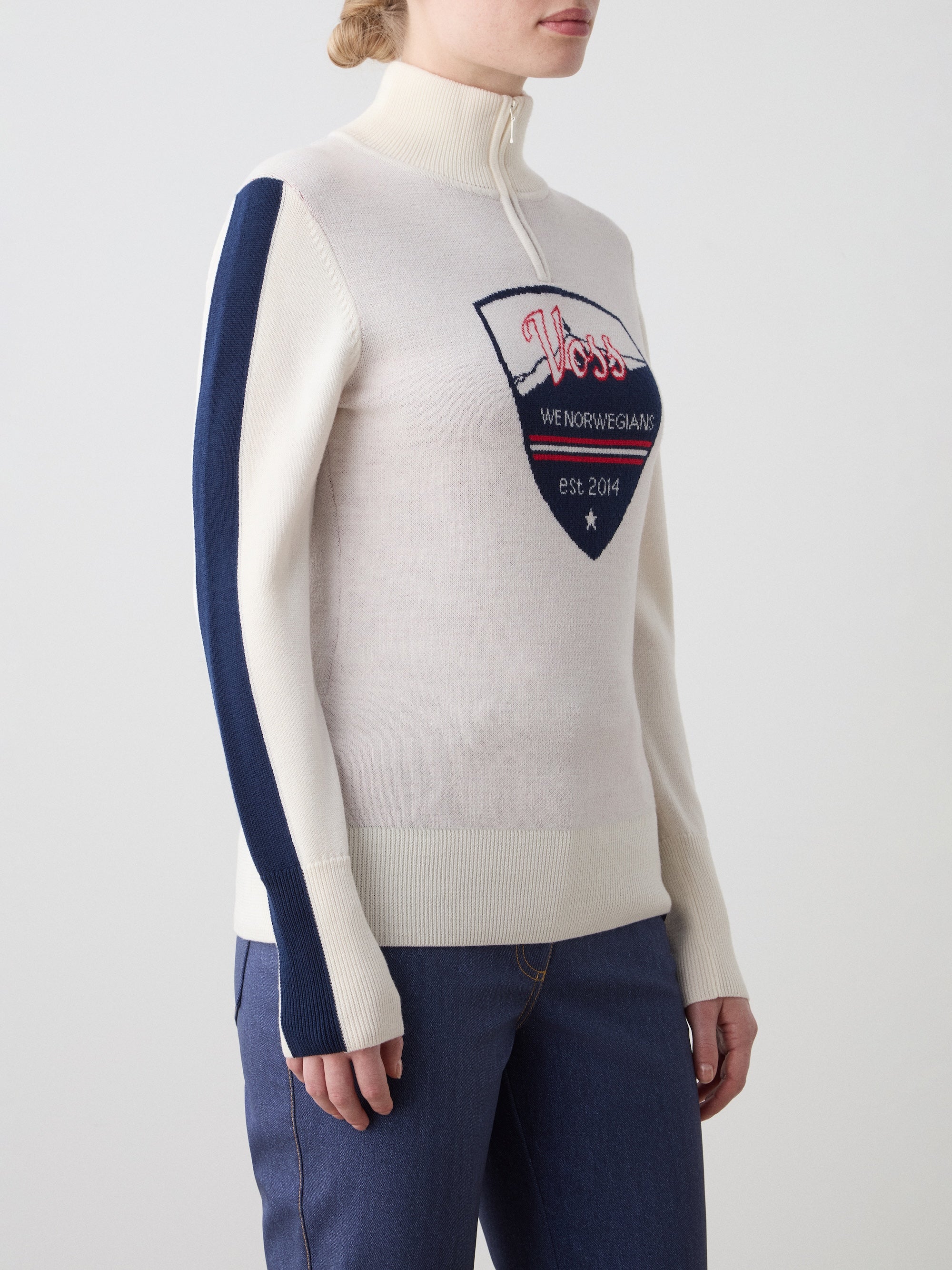 We Norwegians | FW25 | The model is wearing womens Afterski zip-up in cream which has the logo and 1/4th zipper in the front, against an off white background | Picture showing the details of the garment