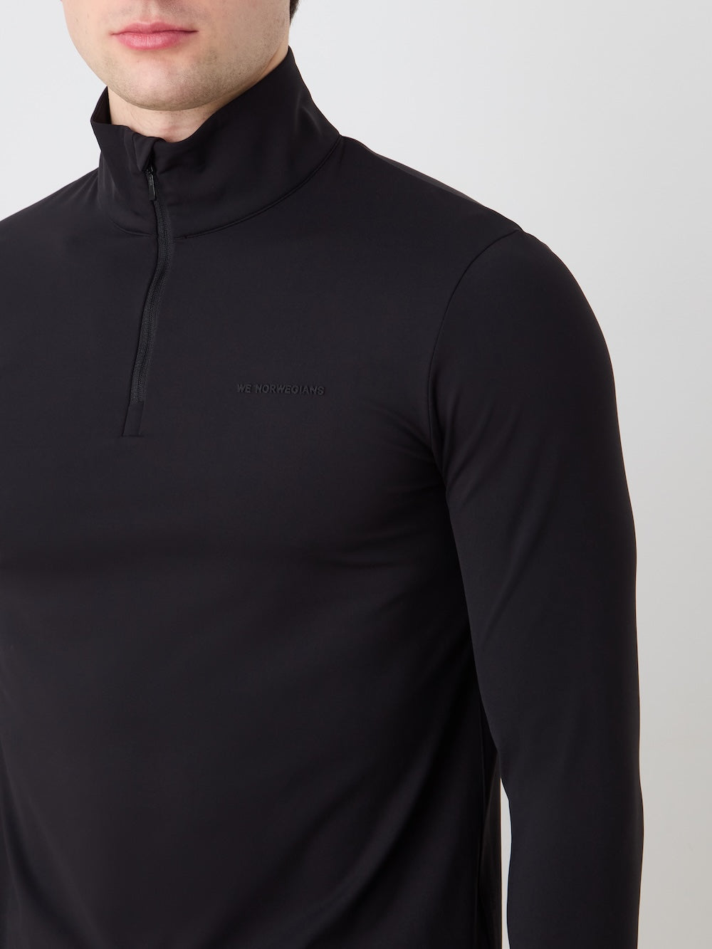 Black long-sleeve shirt with a brand logo on an off white background