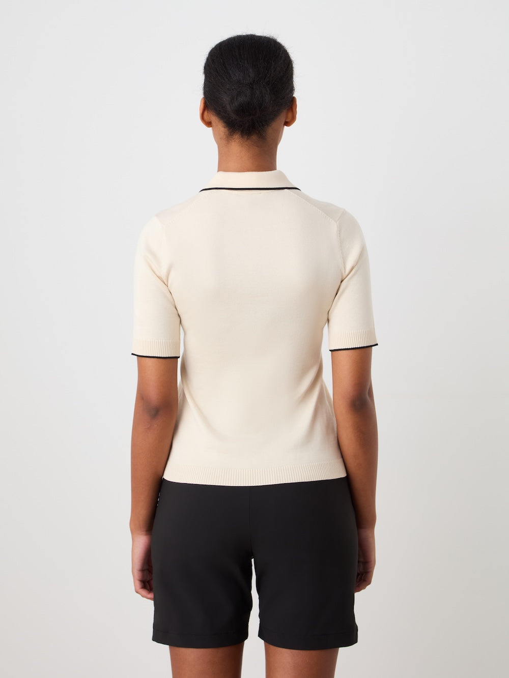 Person wearing a beige polo shirt with black details on a plain background