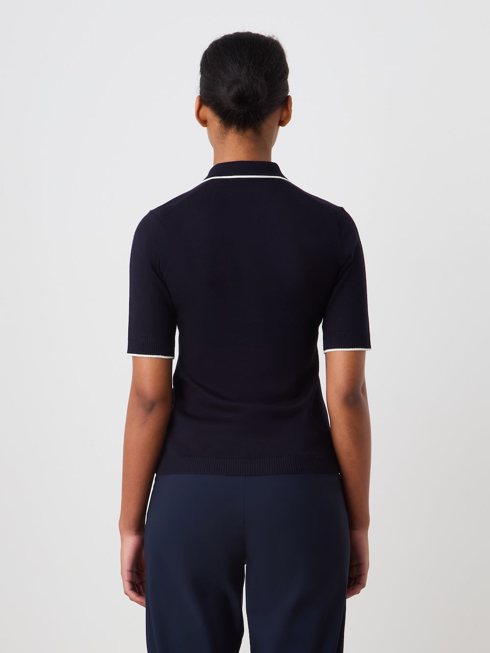 Person wearing a navy polo shirt and pants on a light background