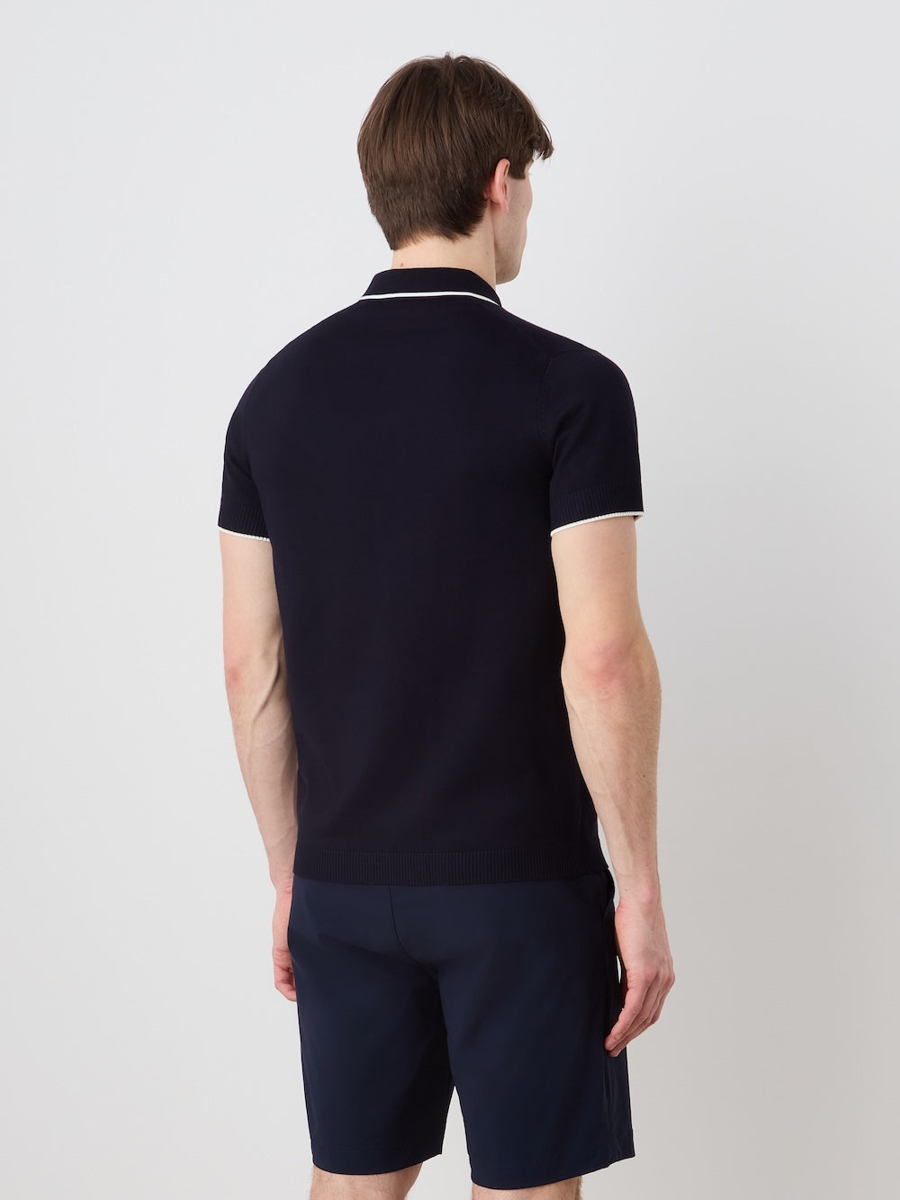 Person wearing a navy polo shirt and shorts on a light background
