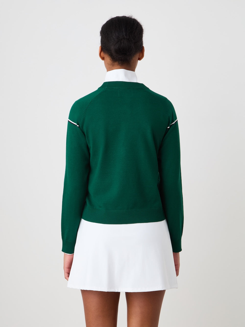 Person wearing a green "Grand Slam" sweater with a white skirt against a plain background