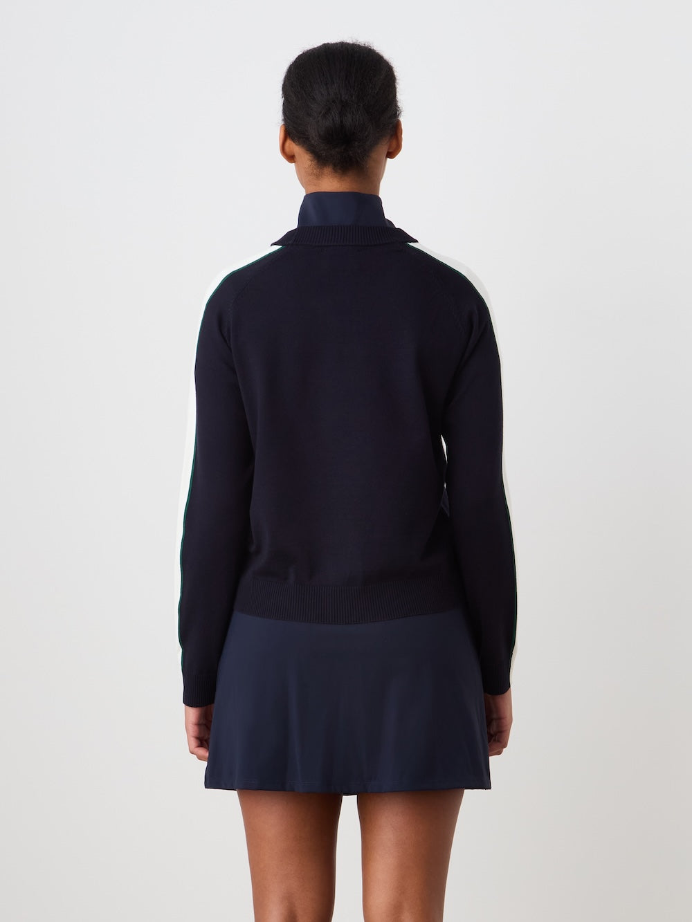 Person wearing a navy blue sweater with "Grand Slam" text in the front, teamed with a navy blue skirt against a light background