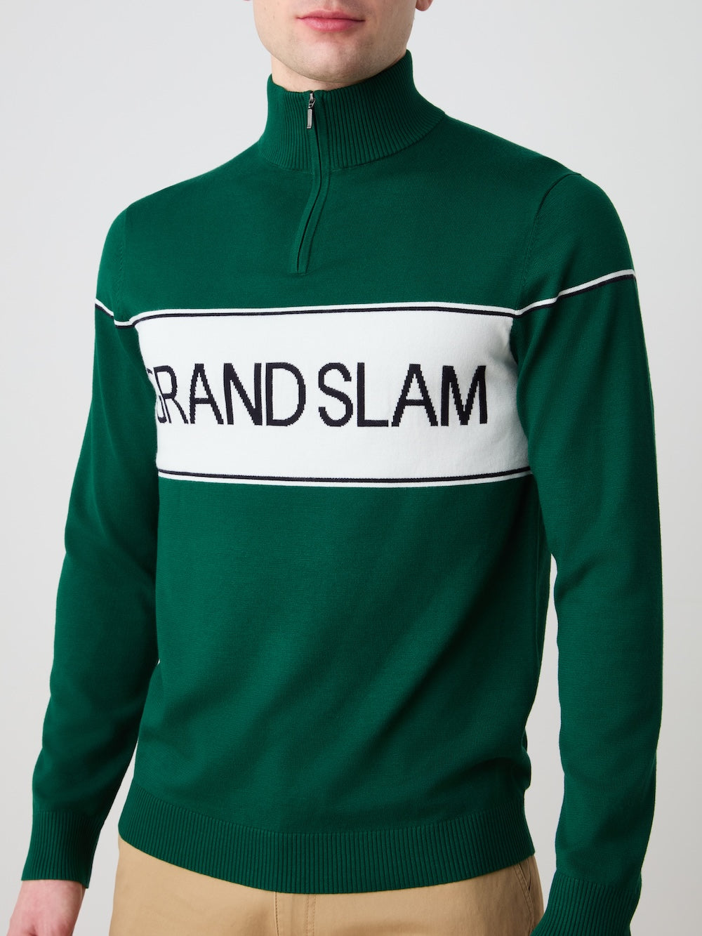 Green sweater with 'Grand Slam' logo worn by a person on a plain background