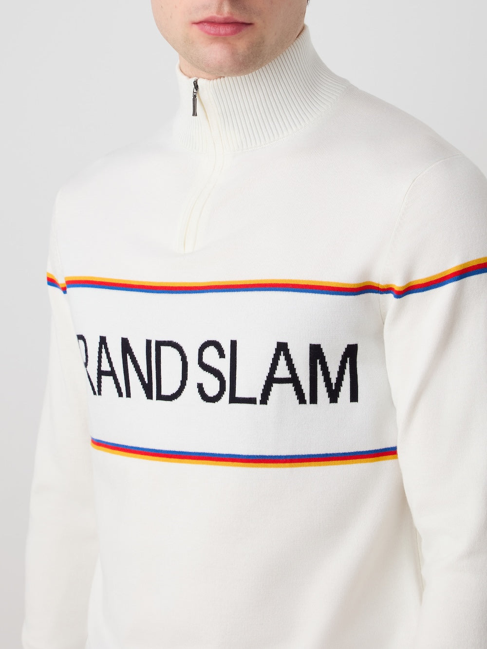 Person wearing an Off White sweater with 'Grand Slam' text and colorful stripes on a plain background
