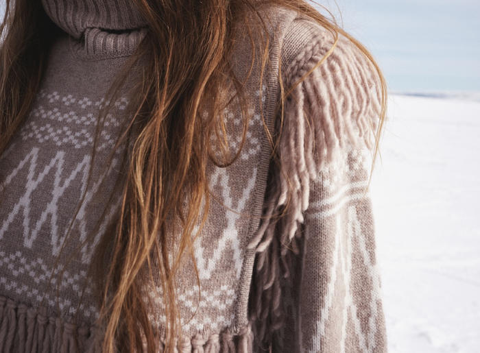We Norwegians | FW25 | Woman wearing the Setesdal Sweater with the Setesdal bib in color - Sand against a backdrop of snowy Geilo