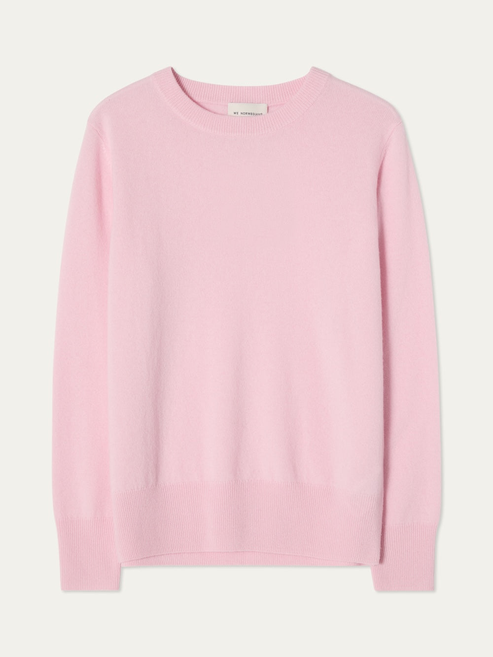 The We Norwegians Blefjell Crewneck Women is a light pink, 100% cashmere sweater with long sleeves, ribbed crewneck, cuffs, and hem, shown laid flat on a white background.