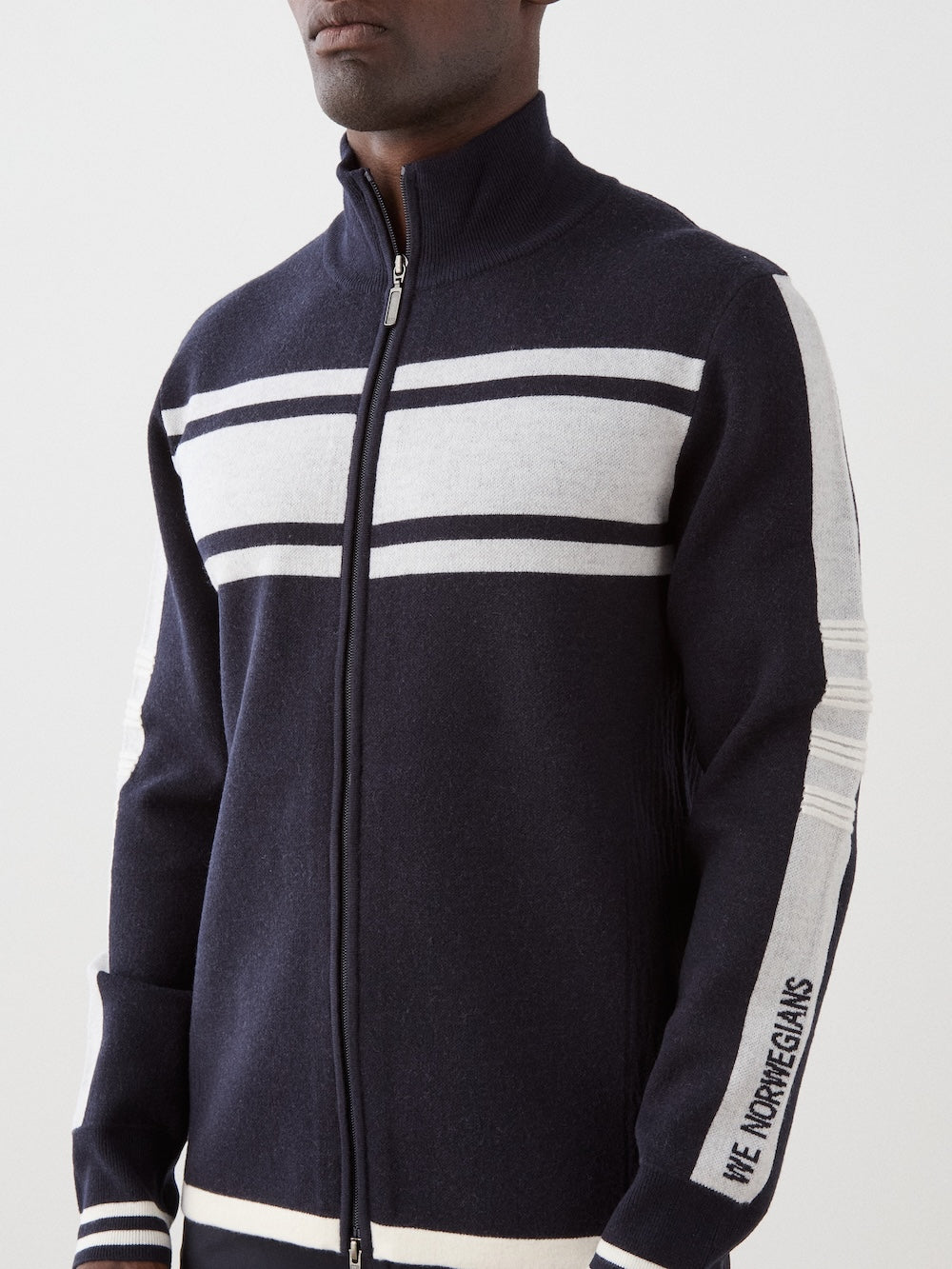 We Norwegians | FW25 | Mens Rocky Full ZipUp_Navy blue | Model wearing this fine knitted sweater with a 2-way front zipper opening, designed in a retro style with contrasting color blocks on the chest and sleeves | Shot against an off-white background | Close-up