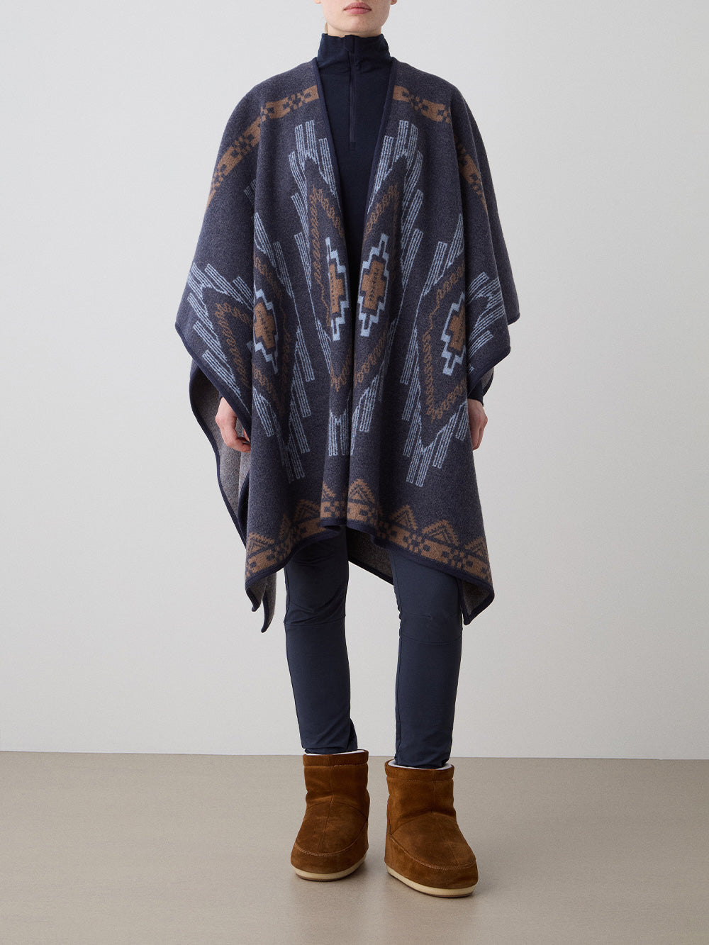We Norwegians_FW25_Womens | Model is wearing the Kautokeino poncho | Navy Blue in color with a jacquard pattern inspired by Native and Indigenous American art | Made with boiled merino wool | Front view