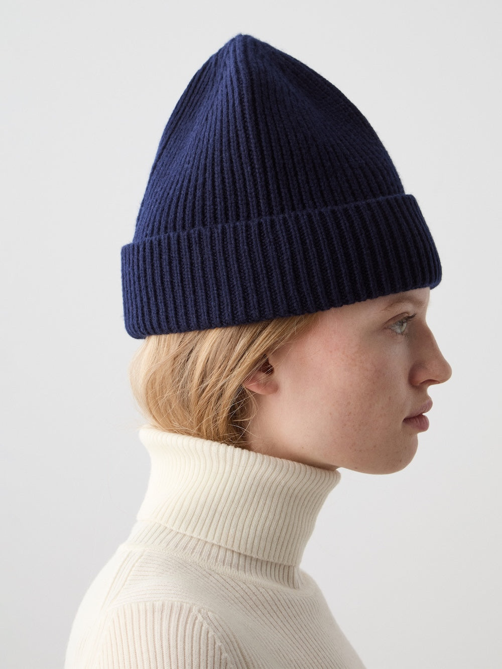 We Norwegians | FW25 | Dal Hat | Model wearing a knit beanie in navy blue against an off-white background