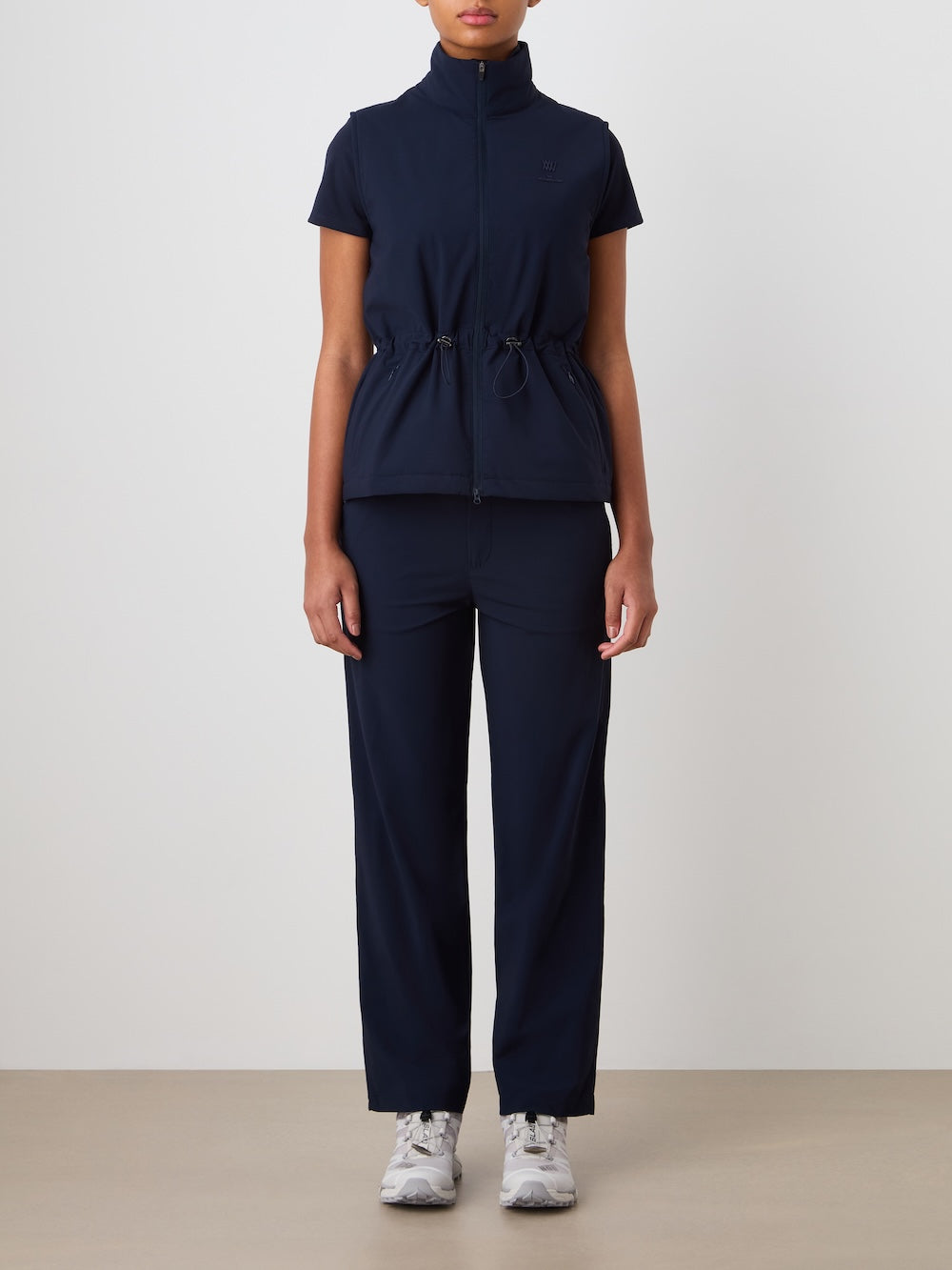 Person wearing a navy blue golf vest with a matching top and pants on a plain background