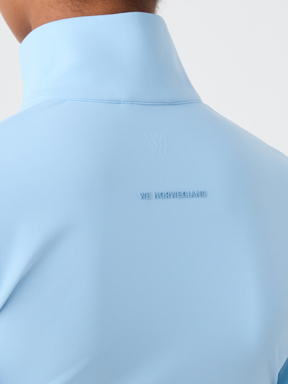 Light blue shirt with a brand logo on a light background