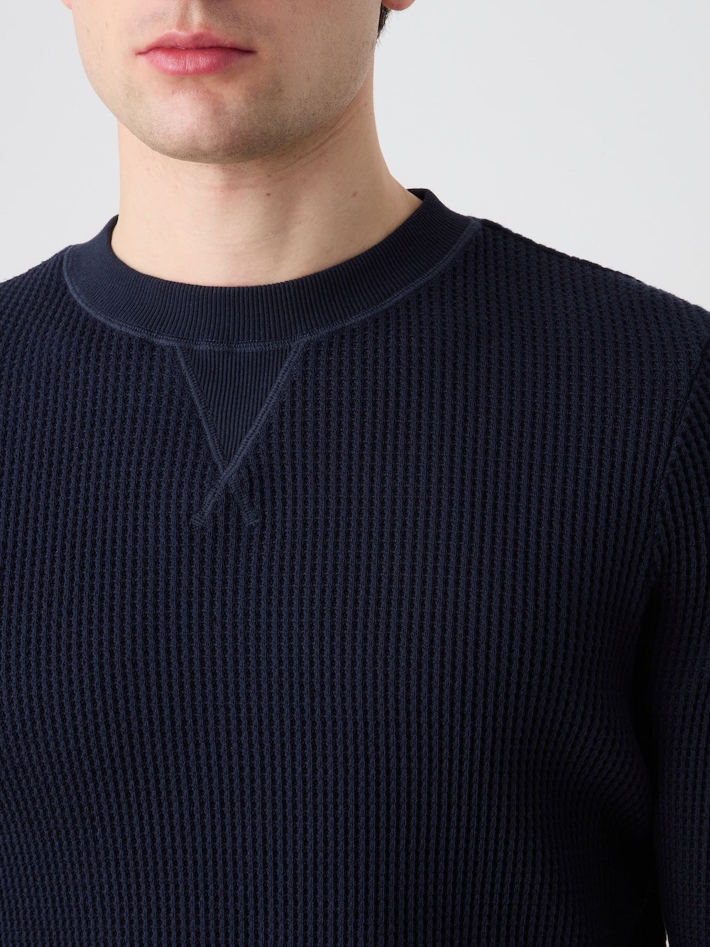 Navy blue crewneck worn by a person on a light background
