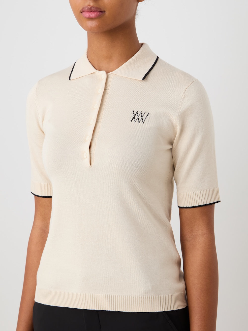 Beige polo shirt with black details worn by a person on a light background