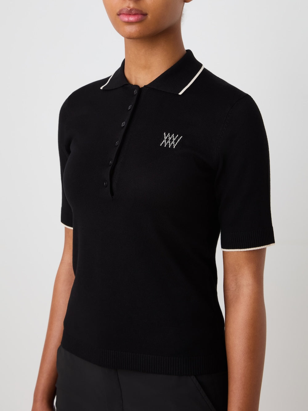 Black polo shirt with white details worn by a person on a light background