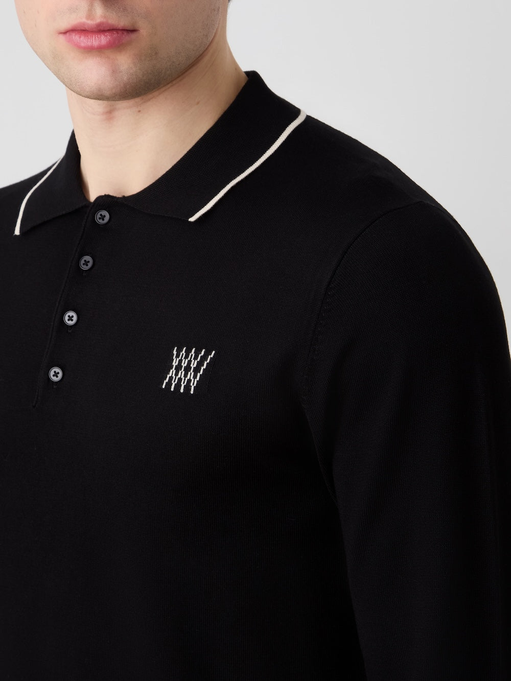 Black polo shirt with white details and logo on a plain background