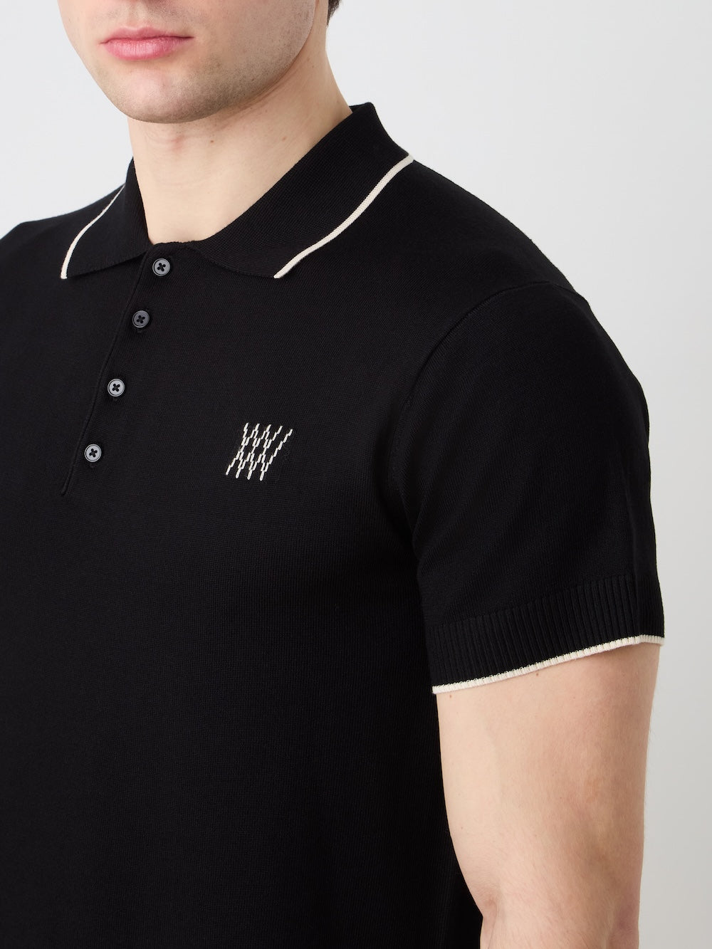 Black polo shirt with white trim worn by a person on a light background