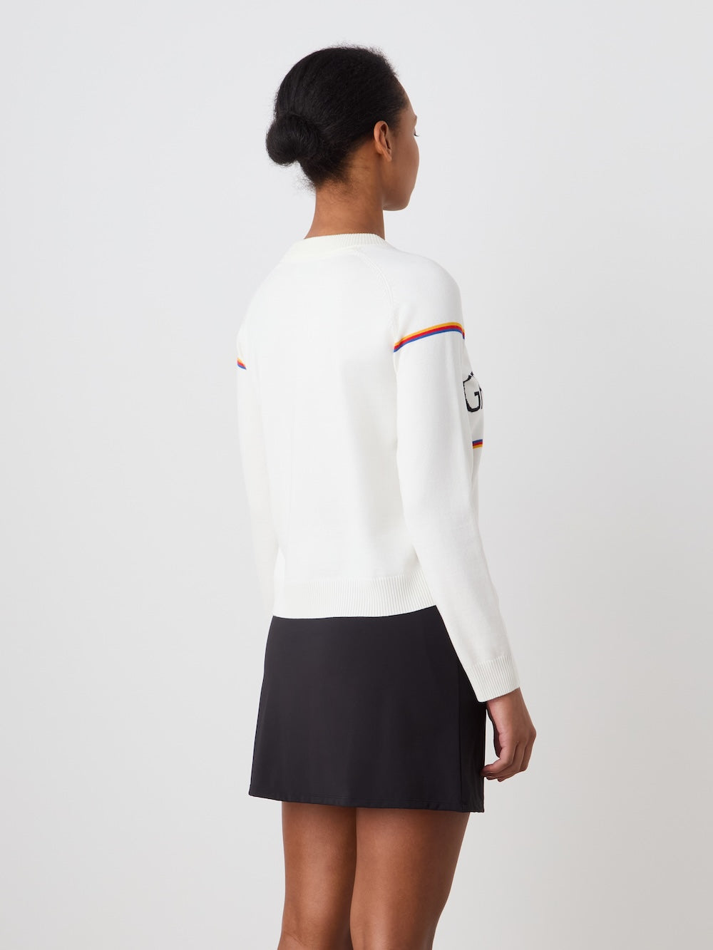 Person wearing a white 'Grand Slam' sweater with a black skirt on a plain background